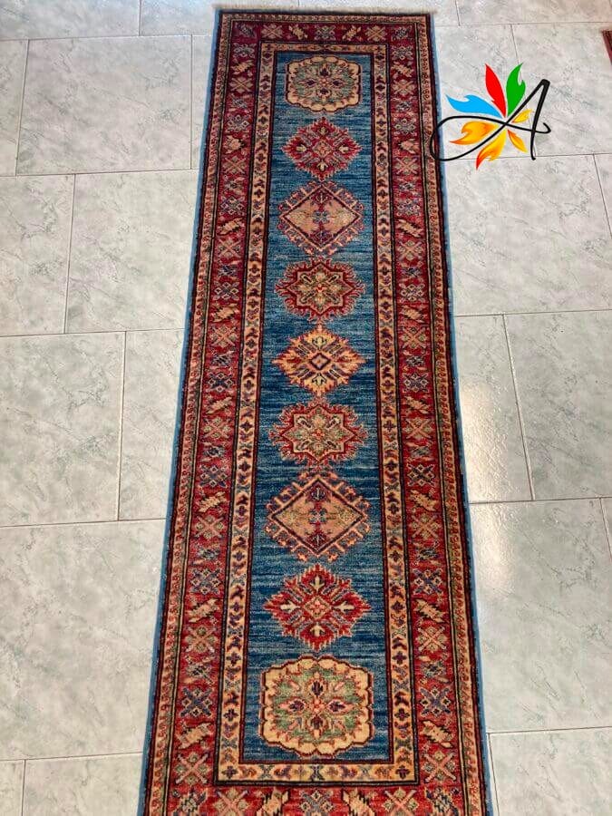 Azerbaijan Tappeti Milano Un lungo tappeto tradizionale con motivi decorati su un pavimento piastrellato.