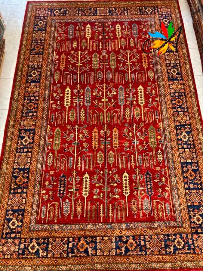 Azerbaijan Tappeti Milano Un tappeto tradizionale dai motivi intricati con campo centrale rosso e bordi blu navy, ornato con motivi geometrici e botanici ripetuti.