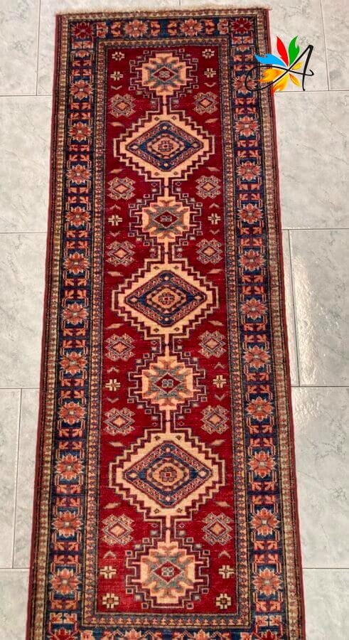 Azerbaijan Tappeti Milano Tappeto tradizionale stretto con motivi intricati su un pavimento piastrellato.