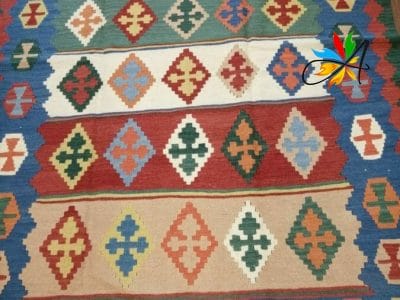 Azerbaijan Tappeti Milano Un tappeto kilim colorato adorna magnificamente un pavimento in legno in uno showroom con splendidi Tappeti Orientali e Tappeti Persiani a Milano.