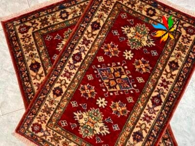 Azerbaijan Tappeti Milano Due tappeti decorati con disegni intricati posizionati su un pavimento piastrellato.