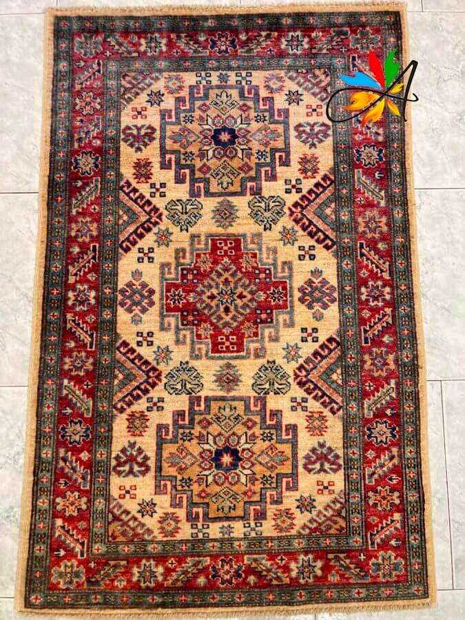 Azerbaijan Tappeti Milano Un tappeto a motivi tradizionali con una spilla a forma di farfalla posizionata nell'angolo in alto a destra.