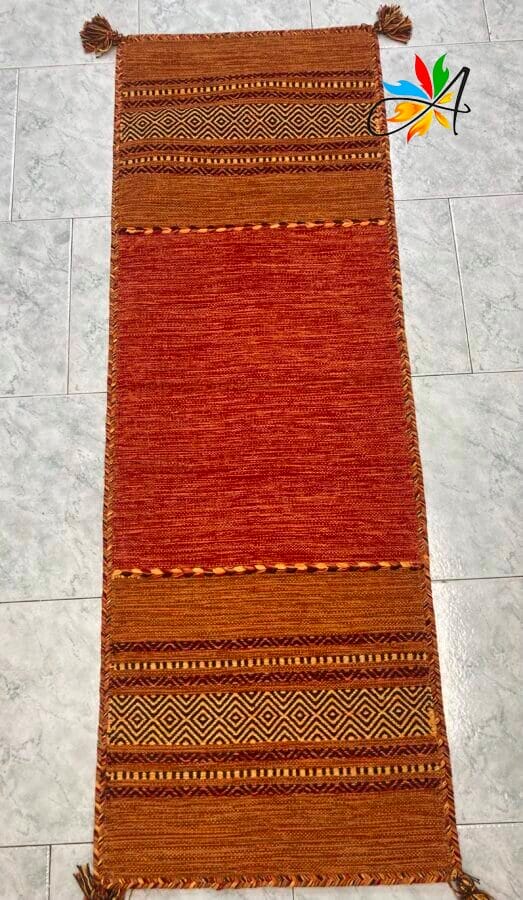 Azerbaijan Tappeti Milano Un tappeto rosso e marrone con nappe sul pavimento disponibile per la vendita in un negozio di tappeti di Milano.