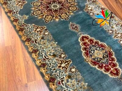 Azerbaijan Tappeti Milano Un elegante tappeto runner dal motivo tradizionale disposto su un pavimento in legno, caratterizzato da intricati disegni nei toni dell'oro, del rosso e del blu.