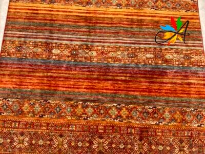 Azerbaijan Tappeti Milano Tappeto dal motivo tradizionale con strisce orizzontali e bordi decorati su una superficie piana.