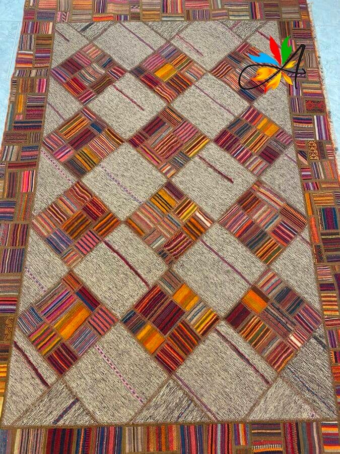 Azerbaijan Tappeti Milano Un tappeto patchwork rettangolare con un motivo geometrico di quadrati e rombi multicolori, caratterizzato da tonalità di rosso, arancione e marrone e da un piccolo motivo a foglia rossa in un angolo.