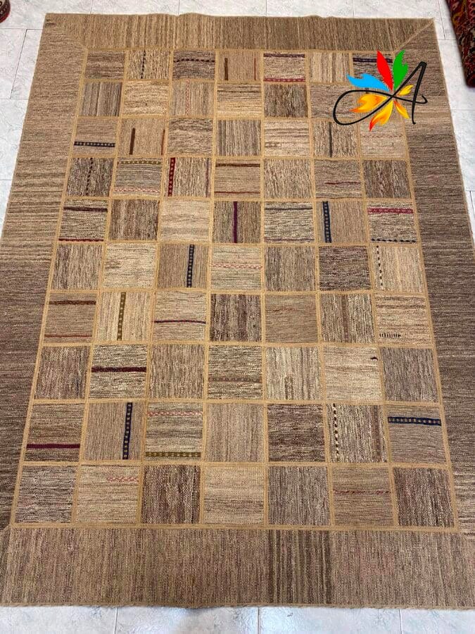 Azerbaijan Tappeti Milano Un grande tappeto rettangolare con un motivo patchwork di quadrati beige, marroni e beige, ognuno caratterizzato da diversi motivi testurizzati.