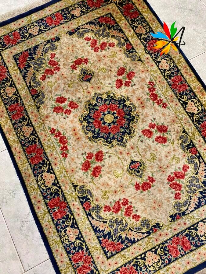 Azerbaijan Tappeti Milano Un tappeto rettangolare decorato in stile persiano con un motivo floreale. Motivi rossi e blu su uno sfondo beige. Un logo colorato è nell'angolo in alto a destra.