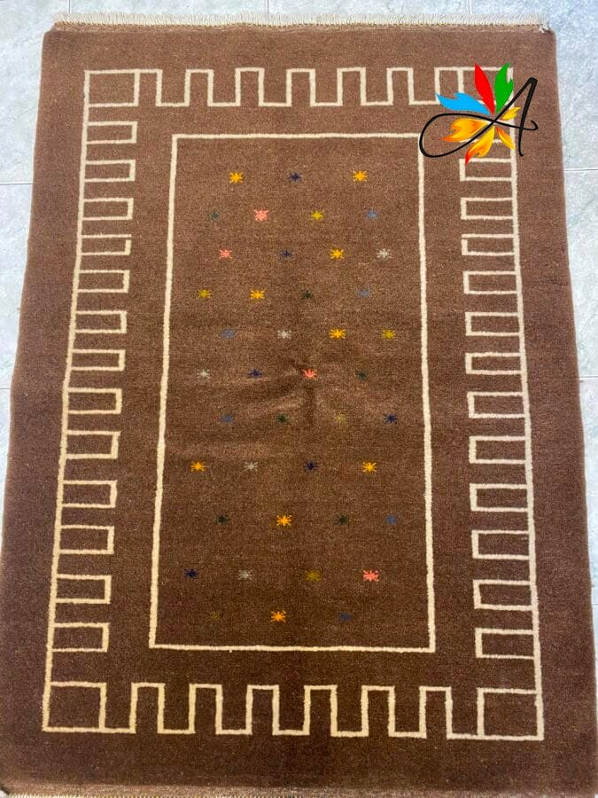 Azerbaijan Tappeti Milano Tappeto marrone con bordo geometrico e piccoli motivi a stella multicolore al centro. Un disegno multicolore che ricorda la lettera "A" si trova nell'angolo in alto a destra.