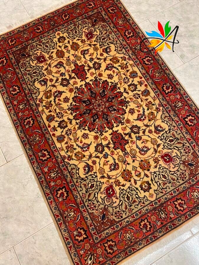 Azerbaijan Tappeti Milano Tappeto rettangolare ornato con intricati motivi floreali in rosso, beige e nero. Un logo colorato è nell'angolo in alto a destra. Posizionato su un pavimento piastrellato.