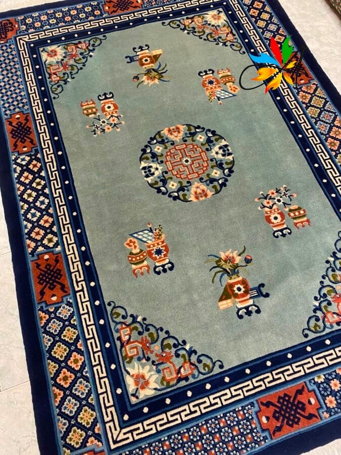 Azerbaijan Tappeti Milano Un tappeto rettangolare con intricati motivi blu, arancioni e verdi e disegni floreali su uno sfondo azzurro.