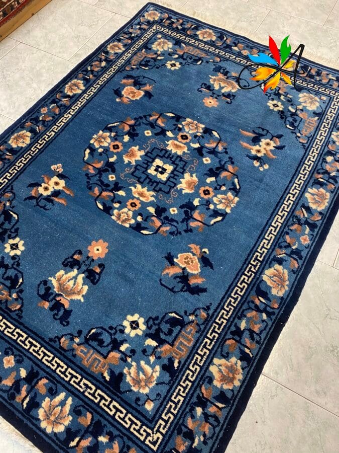 Azerbaijan Tappeti Milano Tappeto orientale blu con motivi floreali e geometrici, steso su un pavimento piastrellato di colore chiaro.