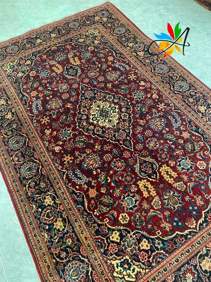 Azerbaijan Tappeti Milano Un tappeto persiano tradizionale con intricati motivi floreali nei toni del rosso, blu navy e crema, adagiato su un pavimento piastrellato.