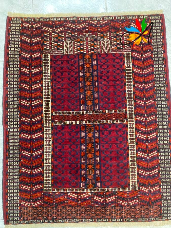 Azerbaijan Tappeti Milano Un tappeto da preghiera con motivi geometrici di colore rosso e una farfalla colorata nell'angolo in alto a destra.