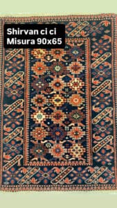 Azerbaijan Tappeti Milano Tappeto Shirvan rettangolare con motivi geometrici in blu scuro, rosso, bianco e giallo, con bordo decorativo. Il testo recita: "Shirvan ci Misura 90x65" con un fiore colorato nell'angolo.