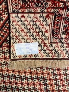Azerbaijan Tappeti Milano Primo piano di un tappeto persiano tradizionale con un'etichetta che indica che è prodotto in Iran.