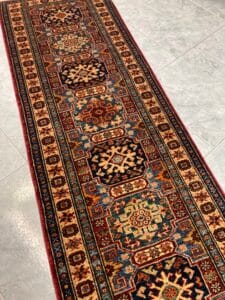 Azerbaijan Tappeti Milano Un tappeto runner lungo e decorato con motivi tradizionali su un pavimento piastrellato.