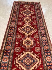 Azerbaijan Tappeti Milano Un tappeto runner con motivi tradizionali posato su un pavimento piastrellato.