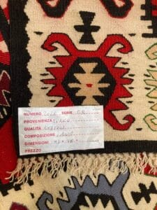 Azerbaijan Tappeti Milano Primo piano di un'etichetta su un tappeto tradizionale che mostra i dettagli sulla sua origine, qualità, dimensione e composizione in italiano.