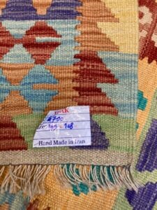 Azerbaijan Tappeti Milano Un primo piano di un tappeto colorato fatto a mano con un'etichetta che indica che è stato prodotto in Iran.