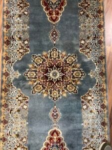 Azerbaijan Tappeti Milano Un tappeto tradizionale decorato con un motivo simmetrico e colori ricchi, caratterizzato da un prominente disegno a medaglione centrale.