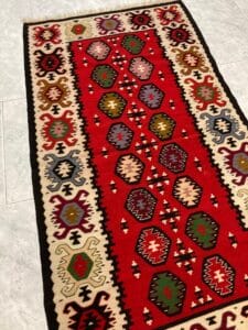 Azerbaijan Tappeti Milano Un tappeto a motivi tradizionali con un motivo a farfalla su un angolo.