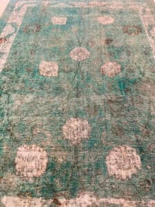 Azerbaijan Tappeti Milano Un tappeto verde con un disegno floreale disponibile per la vendita presso un negozio di tappeti di Milano.