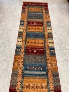 Azerbaijan Tappeti Milano Un tappeto runner colorato e fantasia steso su un pavimento piastrellato.