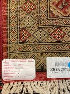 Azerbaijan Tappeti Milano Dettaglio di un tappeto orientale dai motivi intricati, annodato a mano, con etichette di autenticità che ne indicano l'origine, la qualità e le dimensioni.