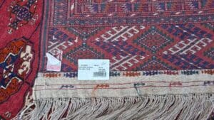 Azerbaijan Tappeti Milano Primo piano di un tappeto decorato con etichetta del prezzo e frange lungo il bordo inferiore.