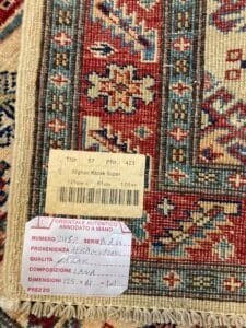 Azerbaijan Tappeti Milano Vista ravvicinata di un'etichetta di tappeto kazak afgano fatto a mano che indica dimensioni, composizione e origine.