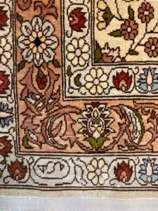 Azerbaijan Tappeti Milano Primo piano di un tappeto a motivi con intricati disegni floreali e una piccola farfalla multicolore adesiva posta su di esso.