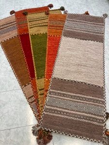 Azerbaijan Tappeti Milano Un gruppo di tappeti persiani colorati con nappe sul pavimento disponibili per la vendita presso un negozio di Milano.