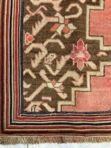 Azerbaijan Tappeti Milano Primo piano di un tappeto a motivi floreali e bordo a strisce.