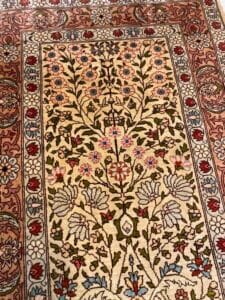 Azerbaijan Tappeti Milano Un tappeto con motivi floreali dettagliati con un oggetto a forma di farfalla sulla parte superiore.