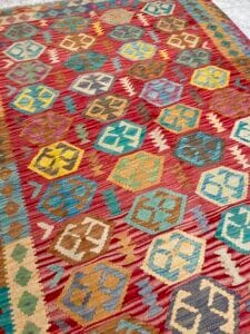 Azerbaijan Tappeti Milano Un tappeto colorato a fantasia con disegni geometrici e una piccola decorazione a farfalla posta sulla parte superiore.