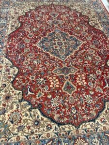Azerbaijan Tappeti Milano Un tappeto orientale dai motivi intricati che mostra una ricca combinazione di rossi, blu e beige, ornato con un piccolo oggetto colorato sulla sua superficie.