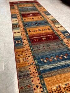 Azerbaijan Tappeti Milano Un tappeto runner con motivi colorati su un pavimento piastrellato.