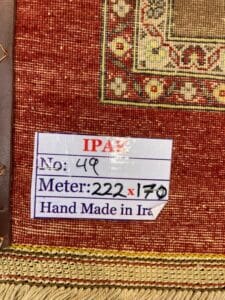 Azerbaijan Tappeti Milano Un'etichetta su un tappeto che indica che è fatto a mano in Iran, con il numero dell'articolo 49 e dimensioni 222×170 cm.