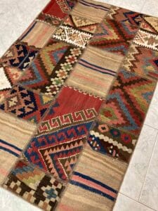 Azerbaijan Tappeti Milano Un tappeto patchwork multicolore con motivi tradizionali e una foglia decorativa sulla superficie.