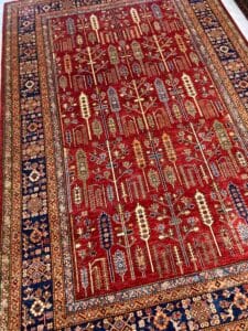 Azerbaijan Tappeti Milano Un tappeto persiano rosso decorato con motivi intricati e dettagli del bordo disposti sul pavimento.