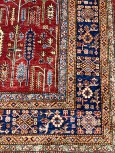 Azerbaijan Tappeti Milano Un tappeto orientale dai motivi intricati che mostra una ricca gamma di disegni e motivi tradizionali, su uno sfondo rosso intenso con tocchi di accenti blu, verdi e crema.