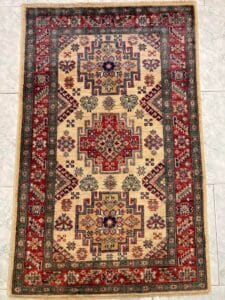 Azerbaijan Tappeti Milano Un tappeto ornato con motivi intricati e una decorazione a forma di farfalla posizionata sul lato destro.