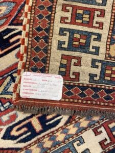 Azerbaijan Tappeti Milano Un primo piano di un tappeto a fantasia con un'etichetta che riporta dettagli come dimensioni, origine e composizione.