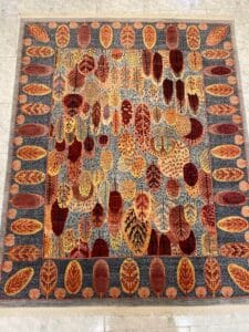 Azerbaijan Tappeti Milano Tappeto colorato con vari motivi di foglie autunnali in arancione, rosso e giallo su uno sfondo grigio-blu.