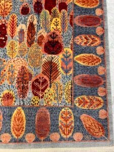 Azerbaijan Tappeti Milano Tappeto colorato con motivi astratti di alberi e foglie in tonalità calde su sfondo grigio, bordato con ovali e foglie.