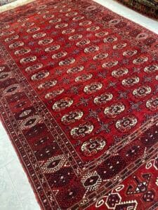 Azerbaijan Tappeti Milano Un tappeto rosso con disegni geometrici giace su un pavimento chiaro.