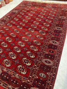 Azerbaijan Tappeti Milano Un tappeto rosso con disegni geometrici su un pavimento piastrellato bianco.