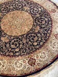 Azerbaijan Tappeti Milano Tappeto persiano rotondo con intricati motivi floreali nei toni del blu navy, crema e rosso, caratterizzato da un motivo centrale a medaglione e bordi con nappe. Motivo a foglia sovrapposta in un angolo.