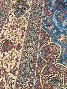 Azerbaijan Tappeti Milano Intricato tappeto in stile persiano con motivi floreali nelle tonalità del rosso, blu, beige e verde, caratterizzato da una girandola colorata nell'angolo in alto a destra.